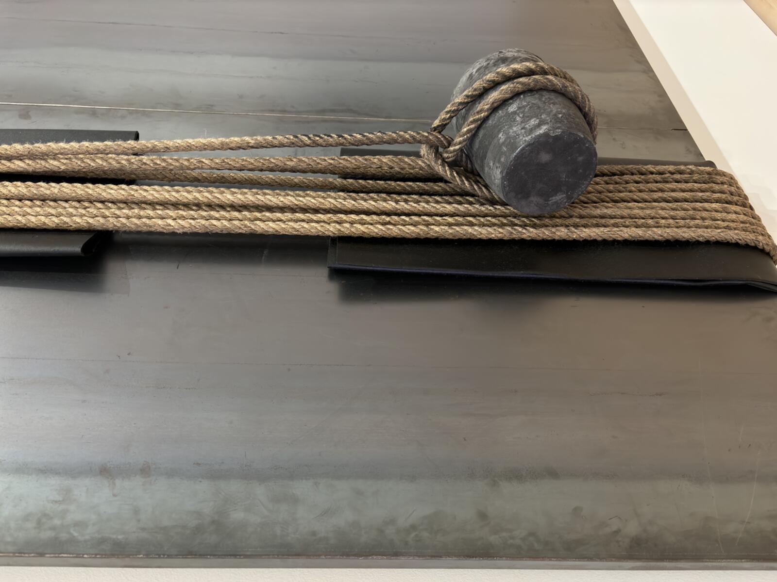 A close-up of a decorative wall piece featuring thick rope wrapped around a cylindrical object mounted on a gray wall. — Interior Design in Newark, CA 94560