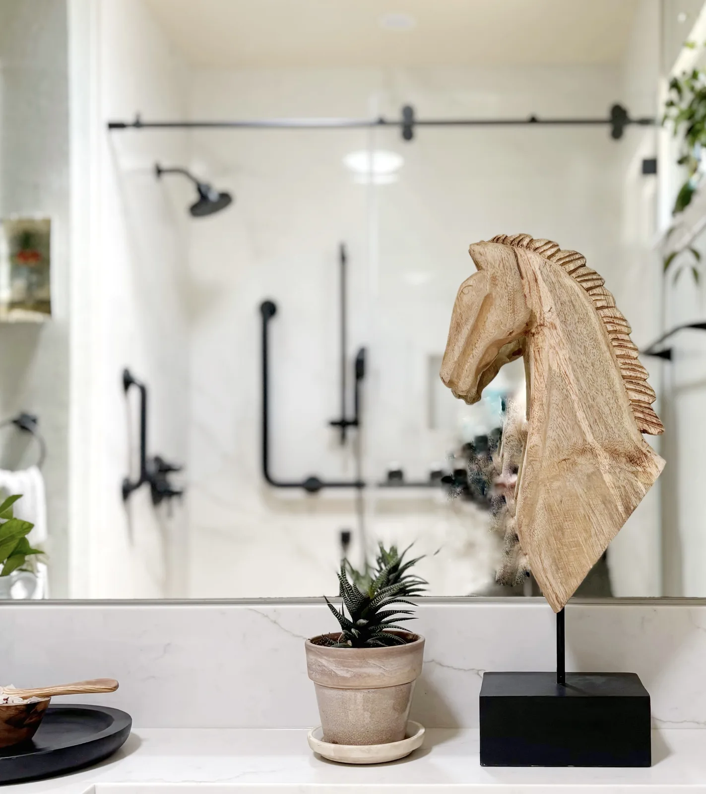 Mirror view showing matte black rain head and integrated grab bars across the walk-in shower