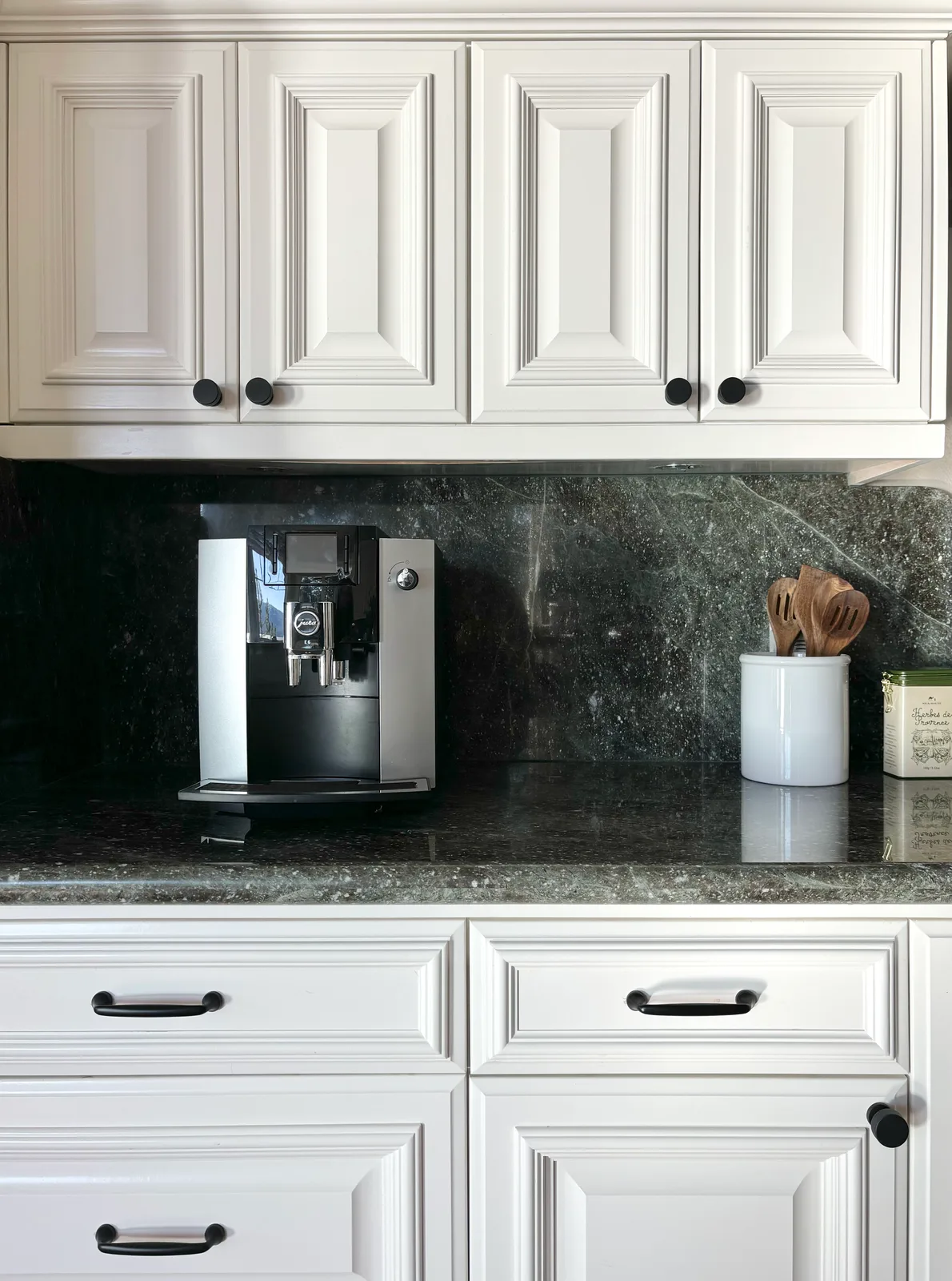 White cabinet panel detail with espresso machine and dark granite counter