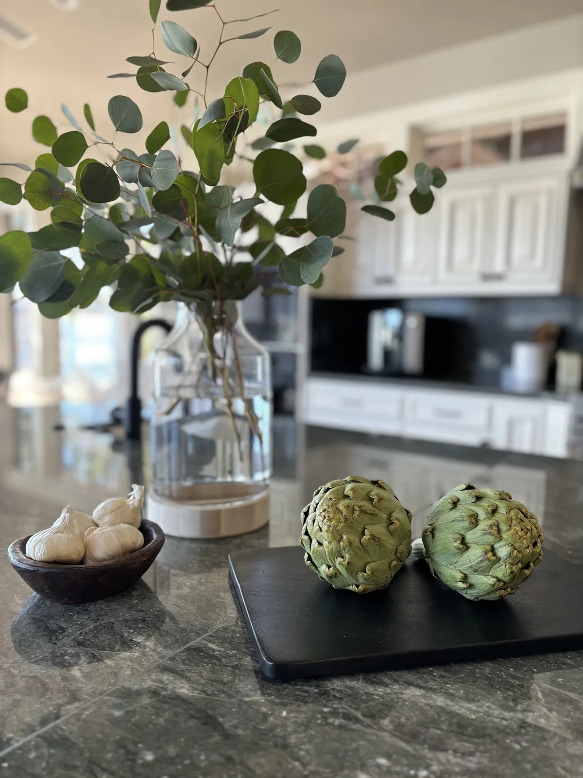 Kitchen island styled with eucalyptus, artichoke sculptures, and salt bowl