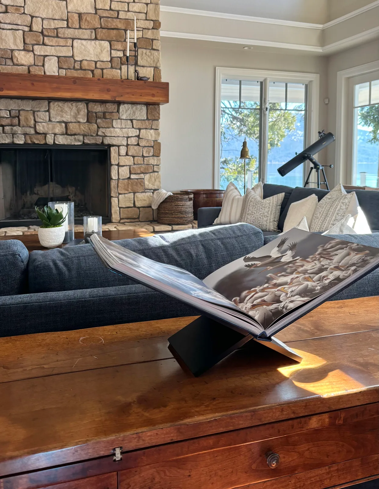 Open design book on coffee table with stone fireplace and sectional in background