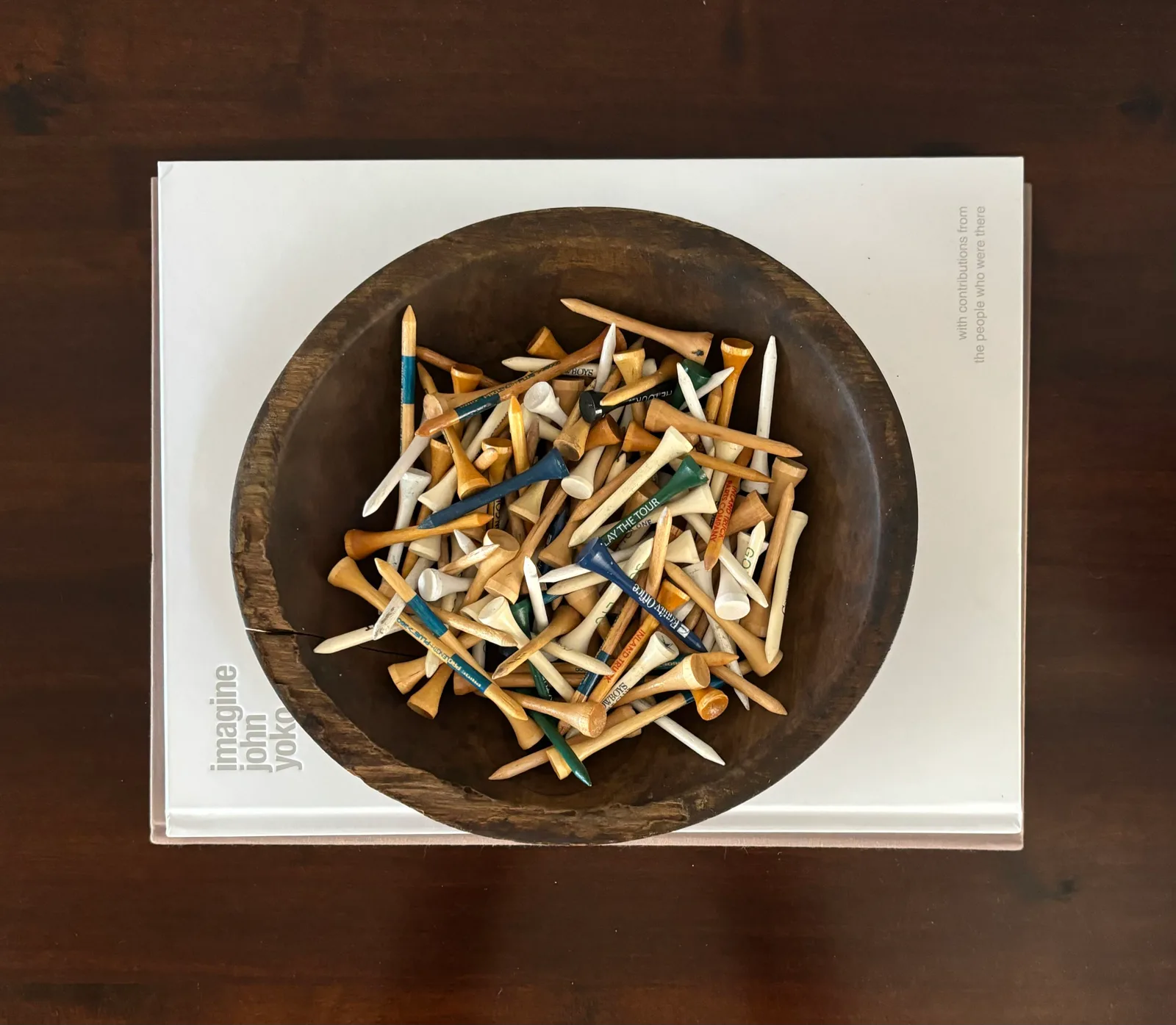 Wooden dough bowl with vintage golf tees on a John Updike "Imagine" book