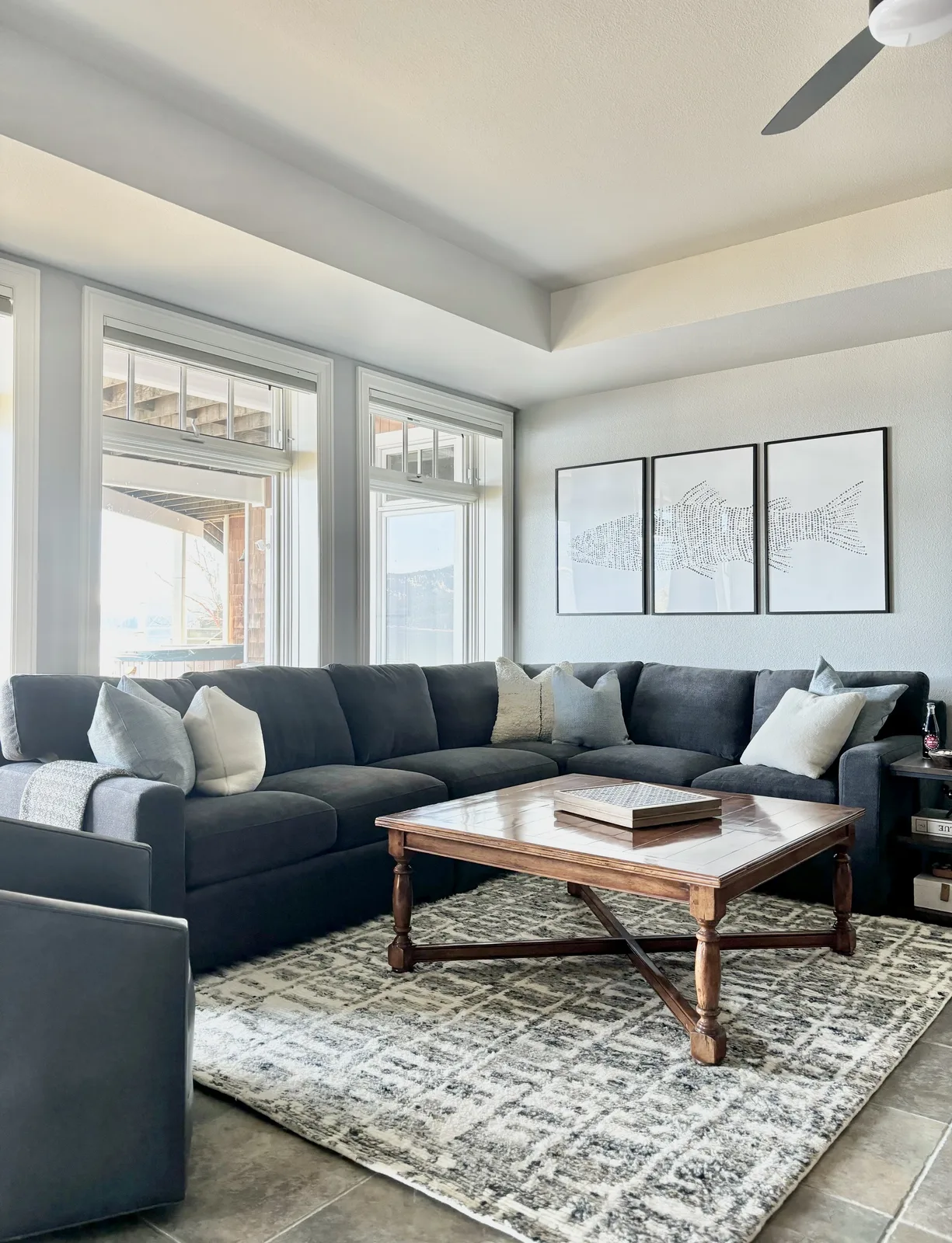 Navy sectional with bird-print gallery wall and travertine coffee table in an open living room