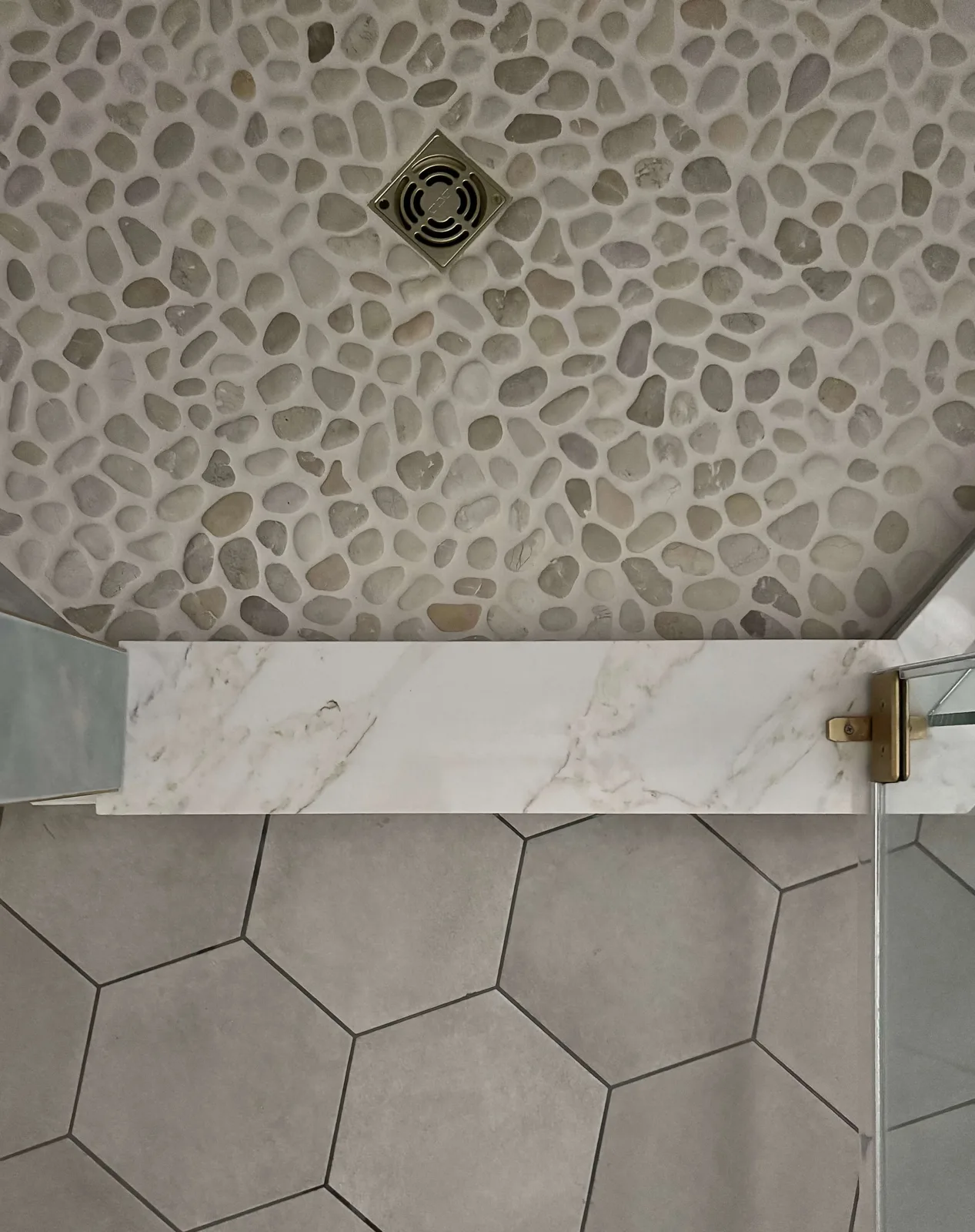 Pebble tile shower floor and drain beside 10" hex bathroom floor tile