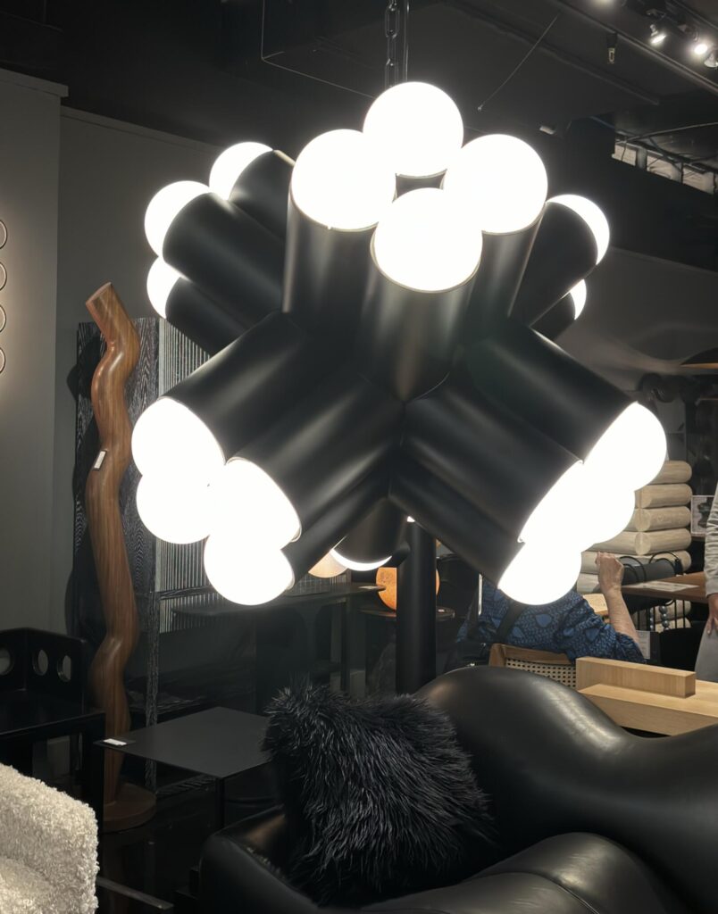 Contemporary interior featuring a sculptural black pendant light with multiple bulbous white globes, alongside textured furni