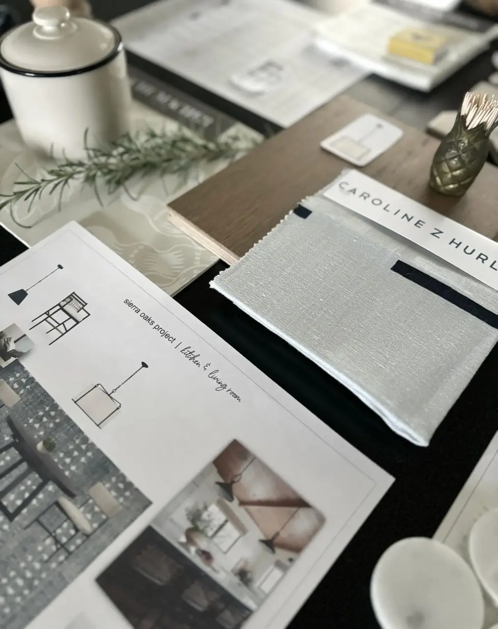 A close-up of interior design materials and project plans including fabric swatches, wood samples, and printed design la — Should I Hire Whole Home Renovation In Sacramento - Interior Designer
