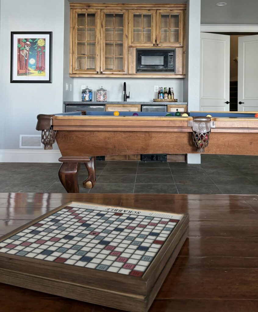Contemporary game room featuring a wooden pool table and a dark wood cabinet with glass doors. The room has tile flooring and