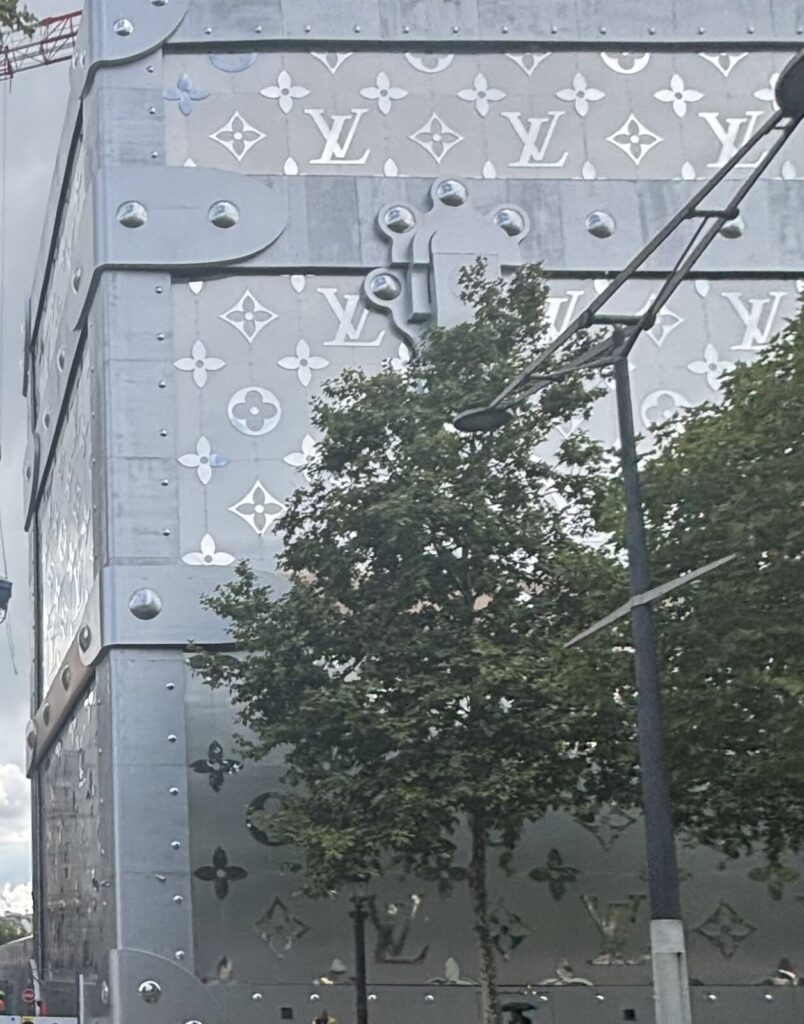 Contemporary building featuring a metallic exterior with floral motifs and a glossy finish, resembling a large artistic box.
