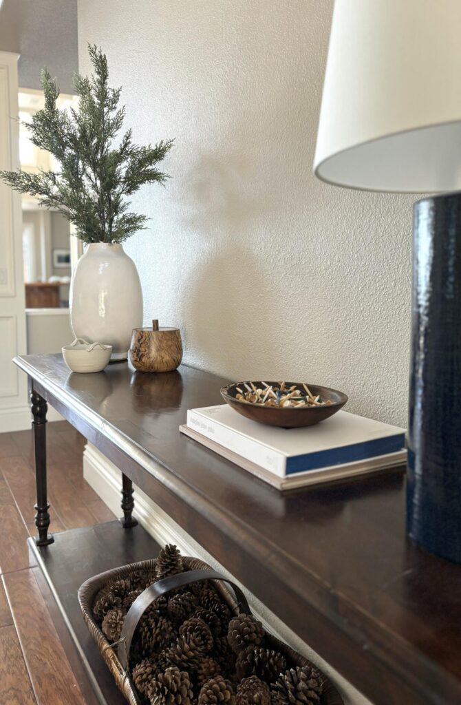 Contemporary entryway featuring a wooden console table with decorative items, including a vase, wooden bowl, and a stack of b