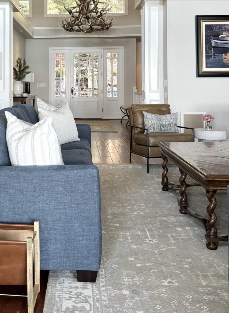 Modern living room with gray walls and a light wood floor, featuring a blue sectional sofa and a vintage-style coffee table.