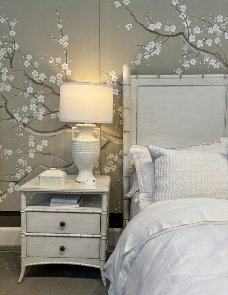 Cozy bedroom featuring a bamboo-style bed frame and nightstand, complemented by a floral patterned wall. The decor includes a
