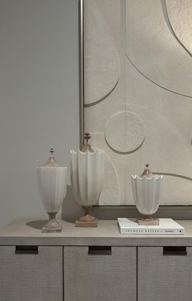 Contemporary interior featuring three decorative vases with a ribbed texture and wooden bases, set against a textured wall ar
