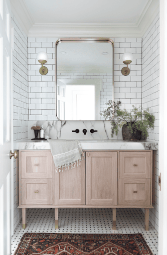 Modern bathroom featuring a white tiled wall with a grid pattern, a light wooden vanity, and a large rectangular mirror. The