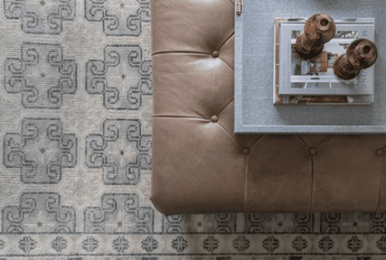Modern living room detail featuring a tufted leather ottoman paired with a textured surface and decorative elements, set on a