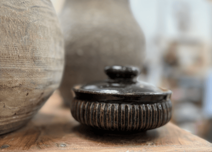 Close-up view of ceramic and pottery pieces, featuring textured surfaces and a rustic aesthetic, displayed on a wooden surfac