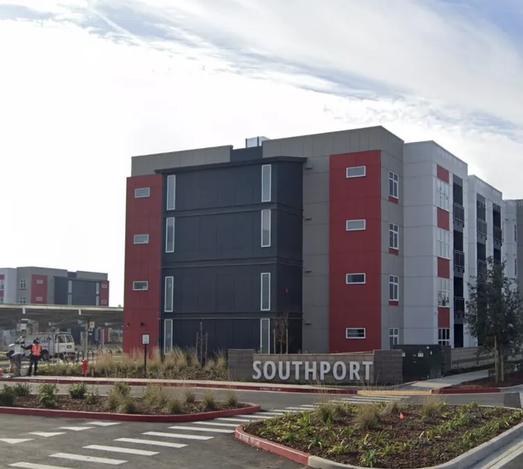 Exterior view of a modern multi-story apartment building with a sign reading SOUTHPORT in front. — Avoid These 12 Atherton Interior Design Red Flags that Cost Clients 500k