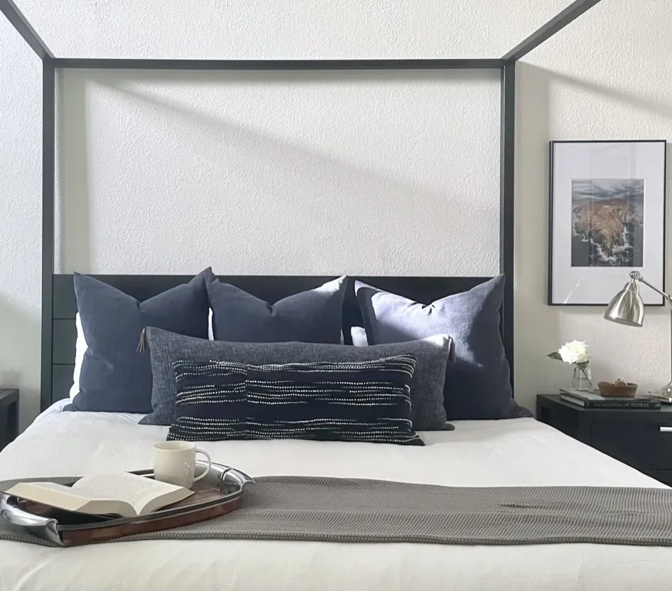 A bedroom with yellow walls, a black dresser, a floral bedspread, and an open door leading to another room
