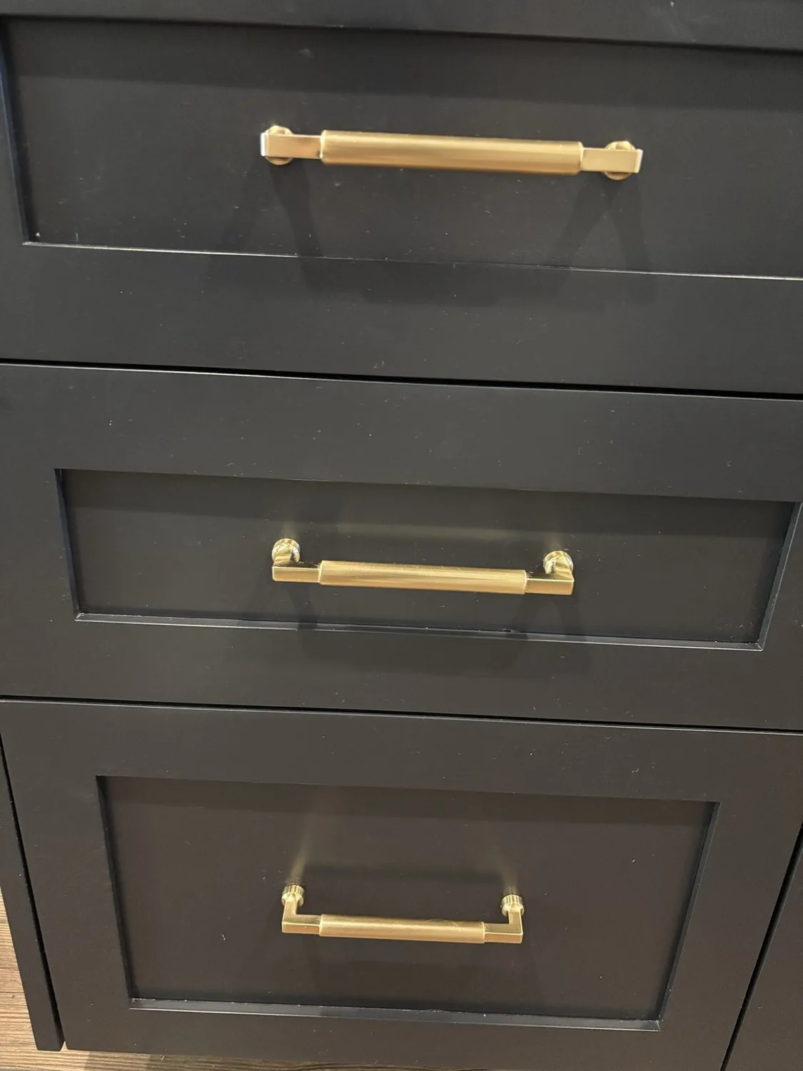 Close-up of black cabinetry drawers with gold handles