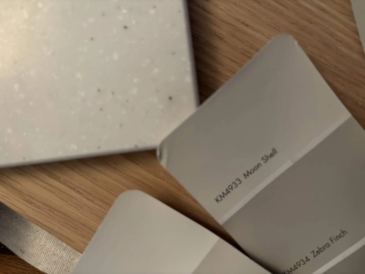 Close-up of paint swatches and a speckled countertop sample on a wooden surface