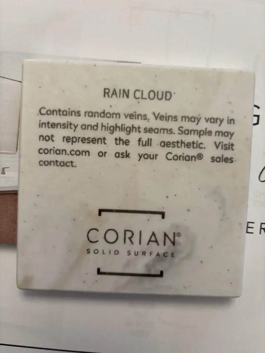 A sample of Corian solid surface material named Rain Cloud with a description of its vein patterns and a website reference
