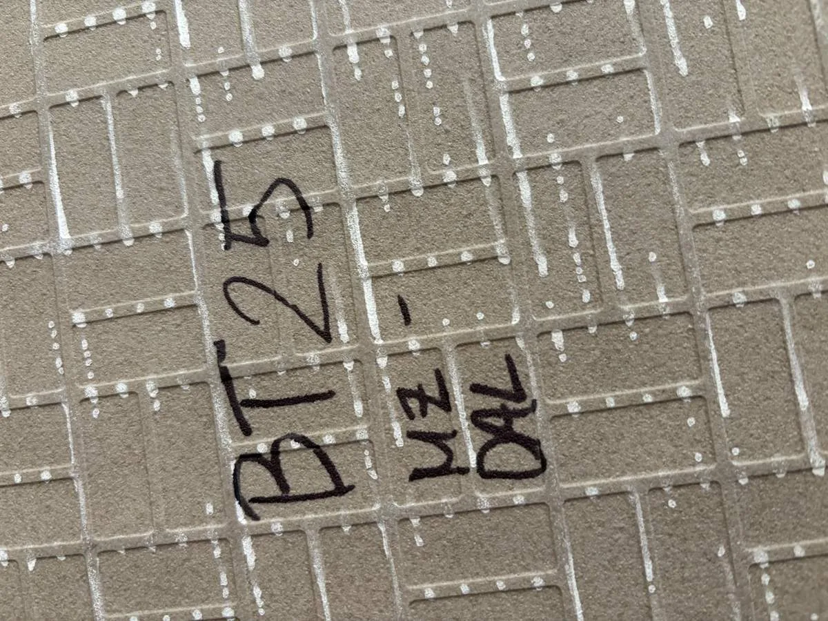 Close-up of a textured beige surface with a grid pattern and handwritten black text