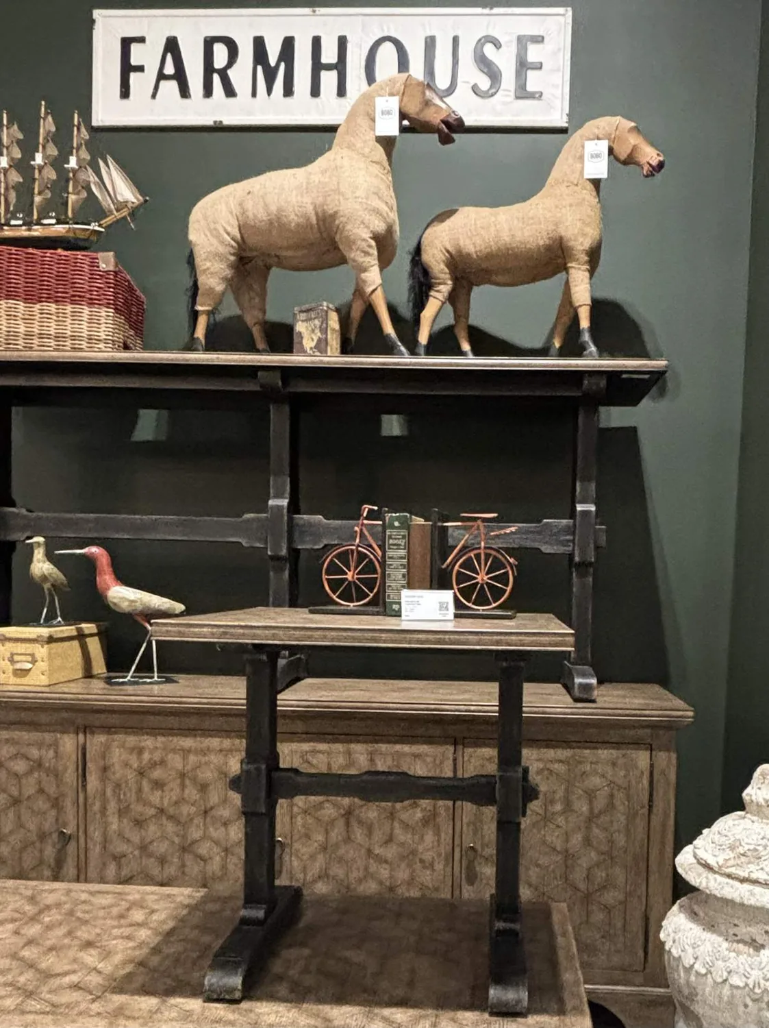 A rustic stone wall with a wooden mantel holding two black candle holders with white candles and a small wooden duck