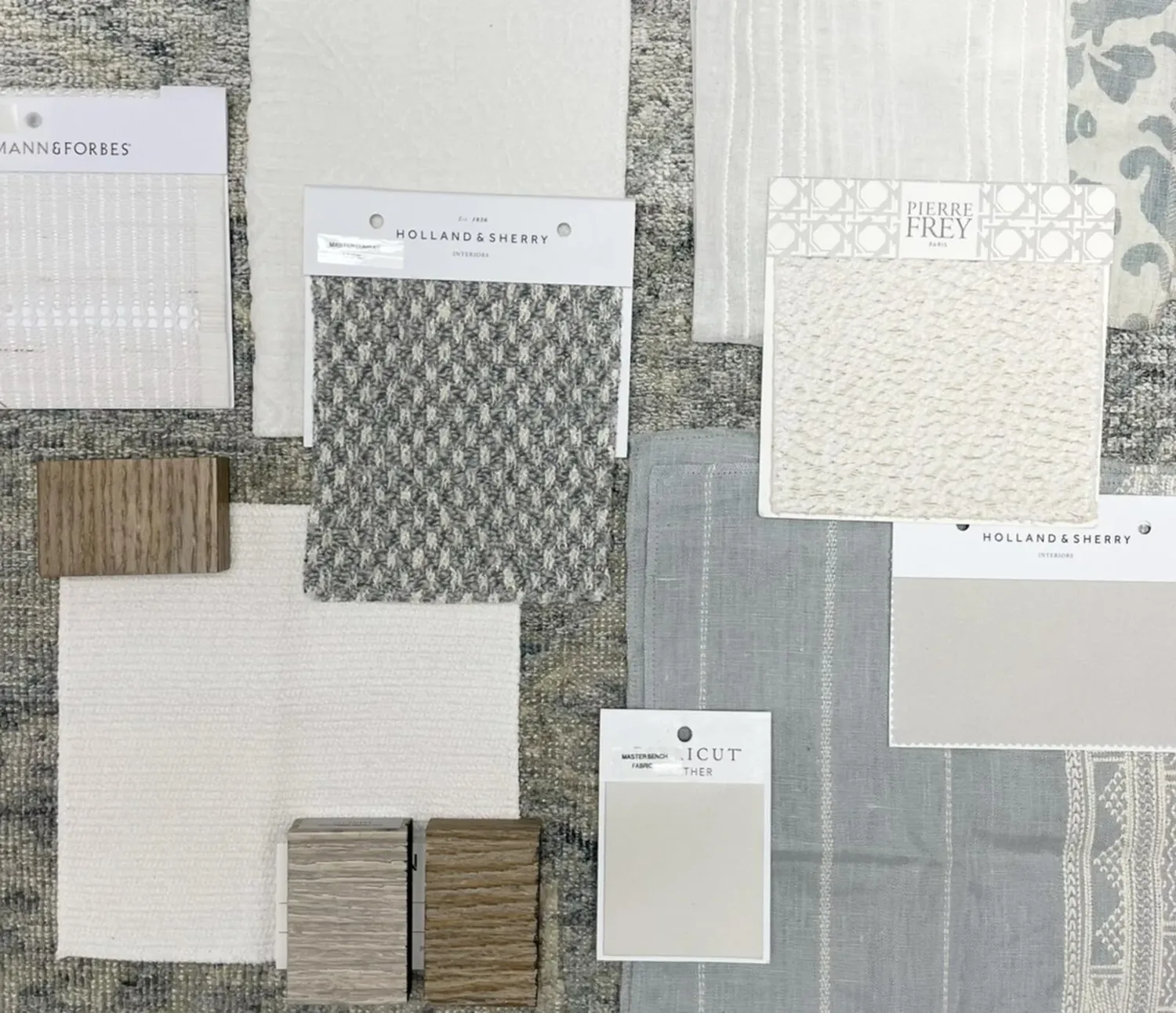 A flat lay of various fabric swatches and wood samples in neutral tones for interior design