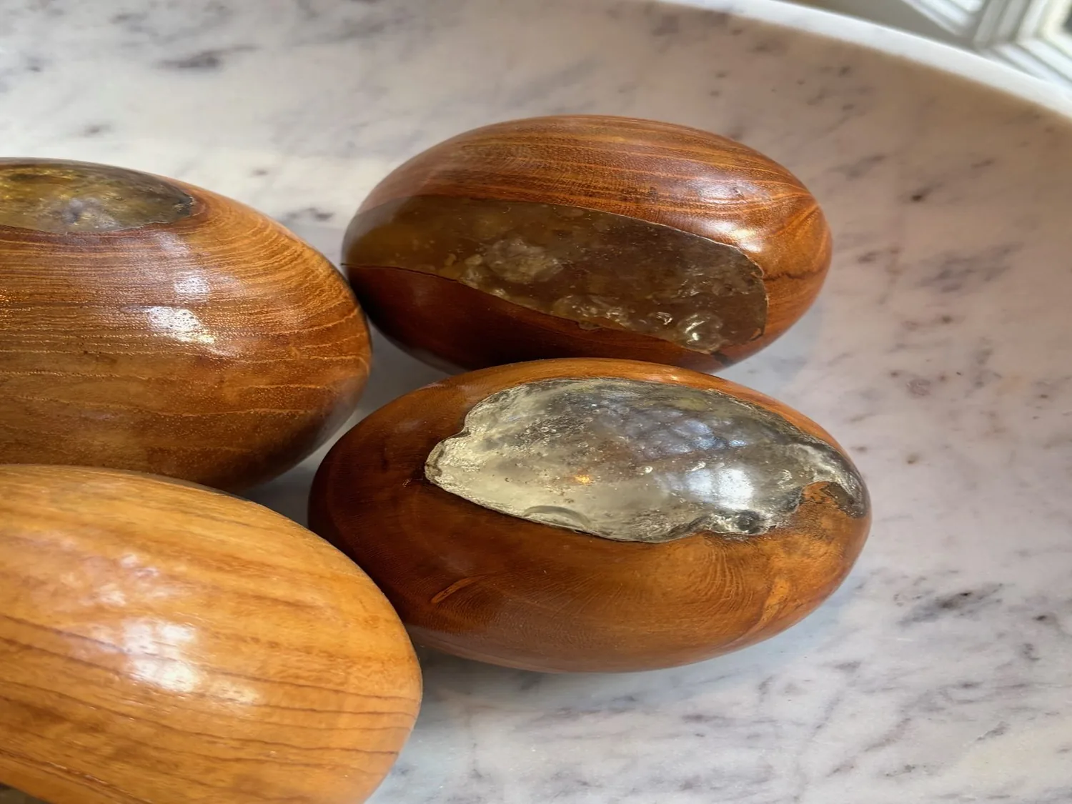 Close-up of decorative wooden spheres with resin inlays placed on a marble surface near a window