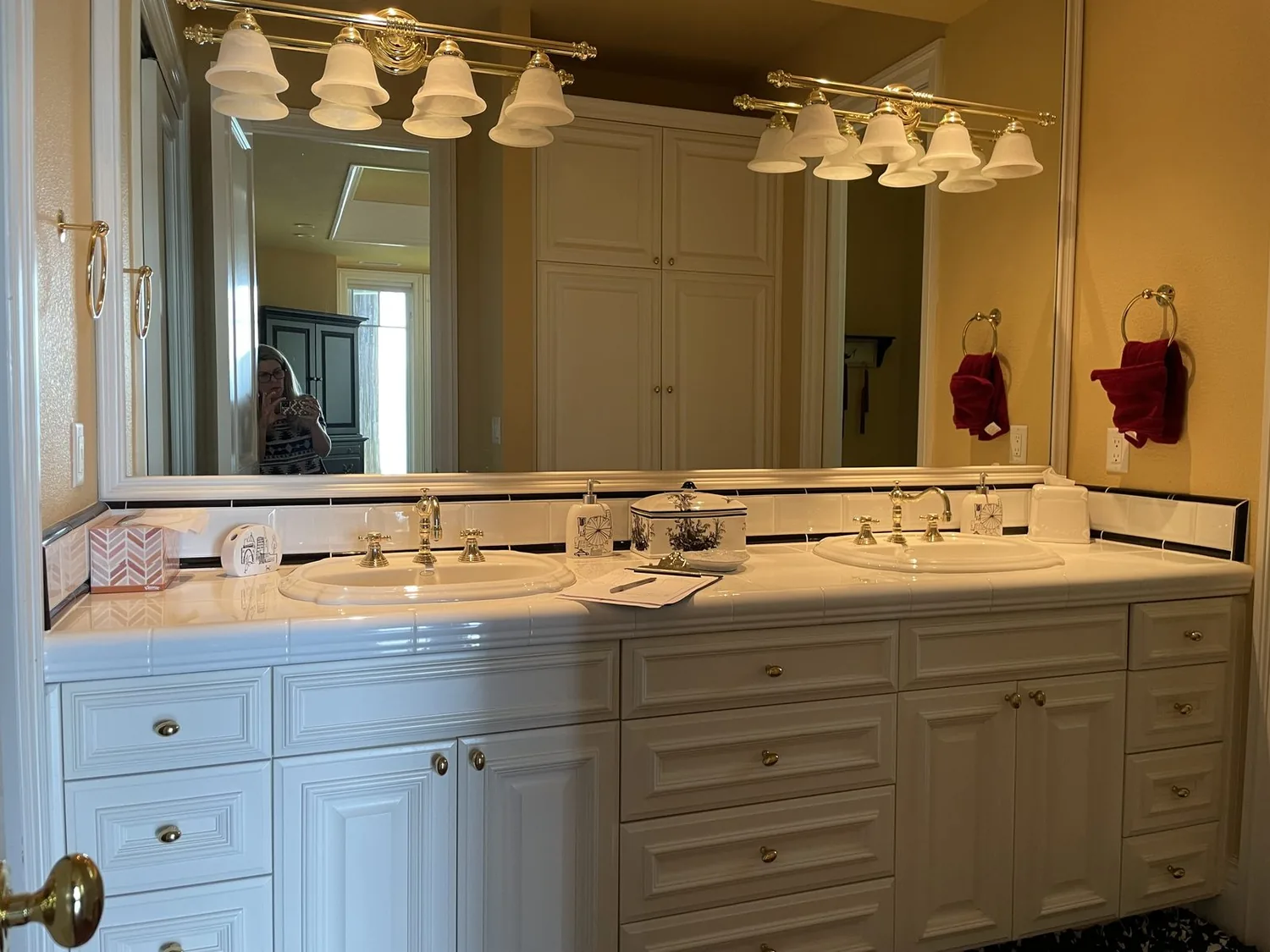 A bathroom vanity with a wooden cabinet, white vessel sink, gold faucet, and decorative items on the countertop
