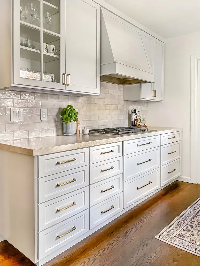A minimalist bathroom with a freestanding bathtub, wooden vanity with a white countertop, gold fixtures, and a large