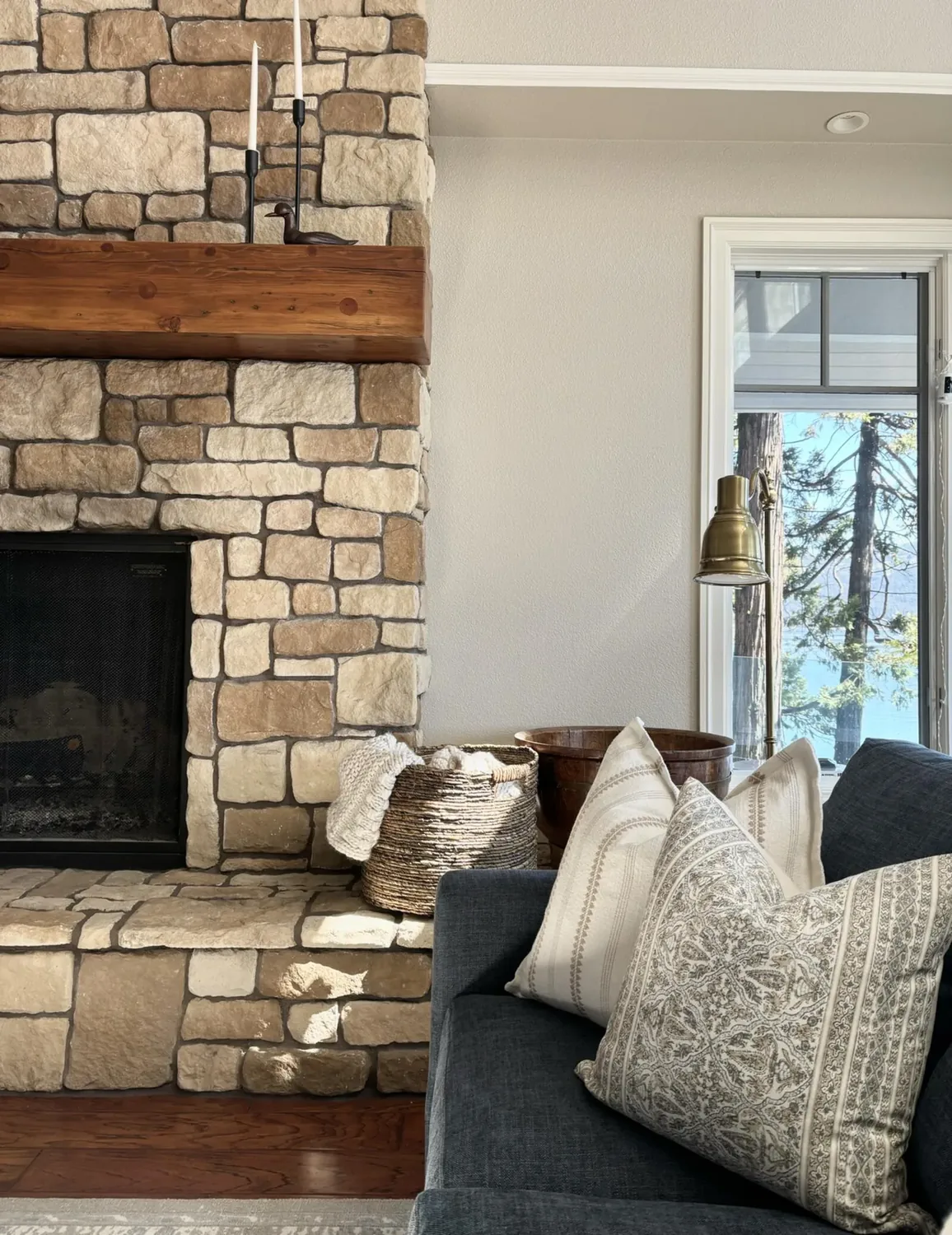 A cozy living room with exposed wooden beams, a fireplace, a bookshelf, and a mix of traditional