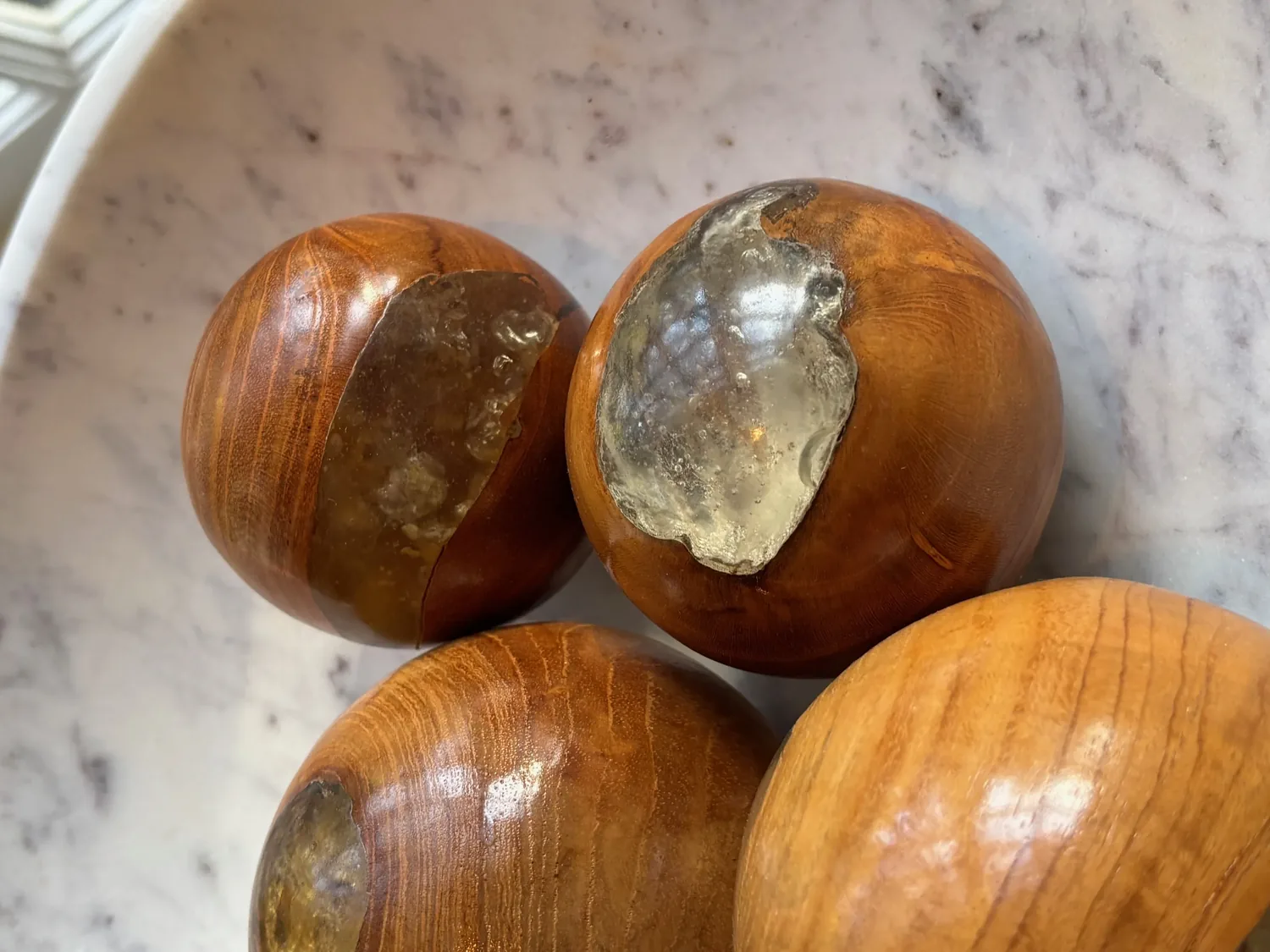 Close-up of decorative wooden spheres with resin inlays on a marble surface