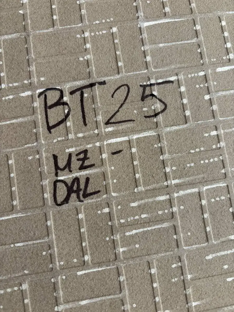 Close-up of a textured beige surface with a grid pattern and handwritten black text