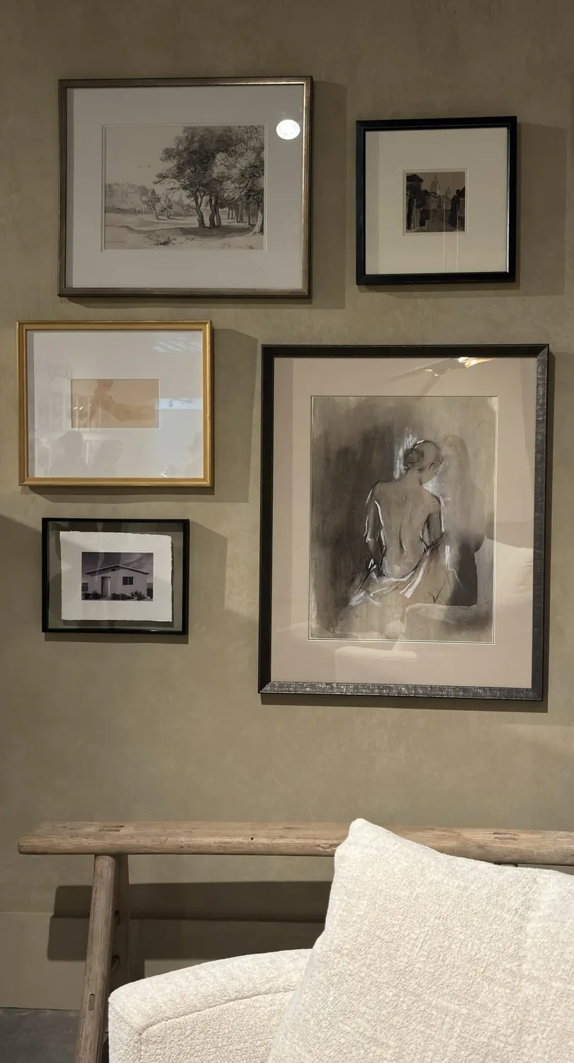A modern living room corner featuring a wooden map wall art, decorative vases, wine bottles with glasses on a console