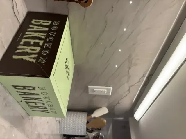 A kitchen countertop with a marble backsplash, a Bouchon Bakery box, and kitchen utensils in a holder