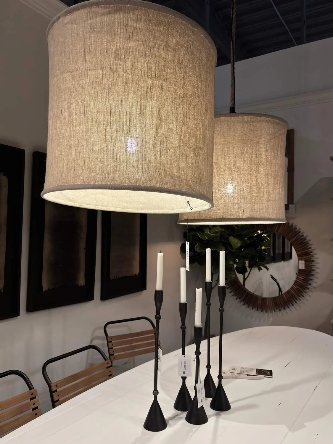 Picture beige pendants over white tables, black candle holders. Add wooden chairs, metal frames, a statement sunburst