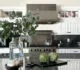 A modern kitchen interior with white cabinetry, a large island with a marble countertop, and stainless steel appliances