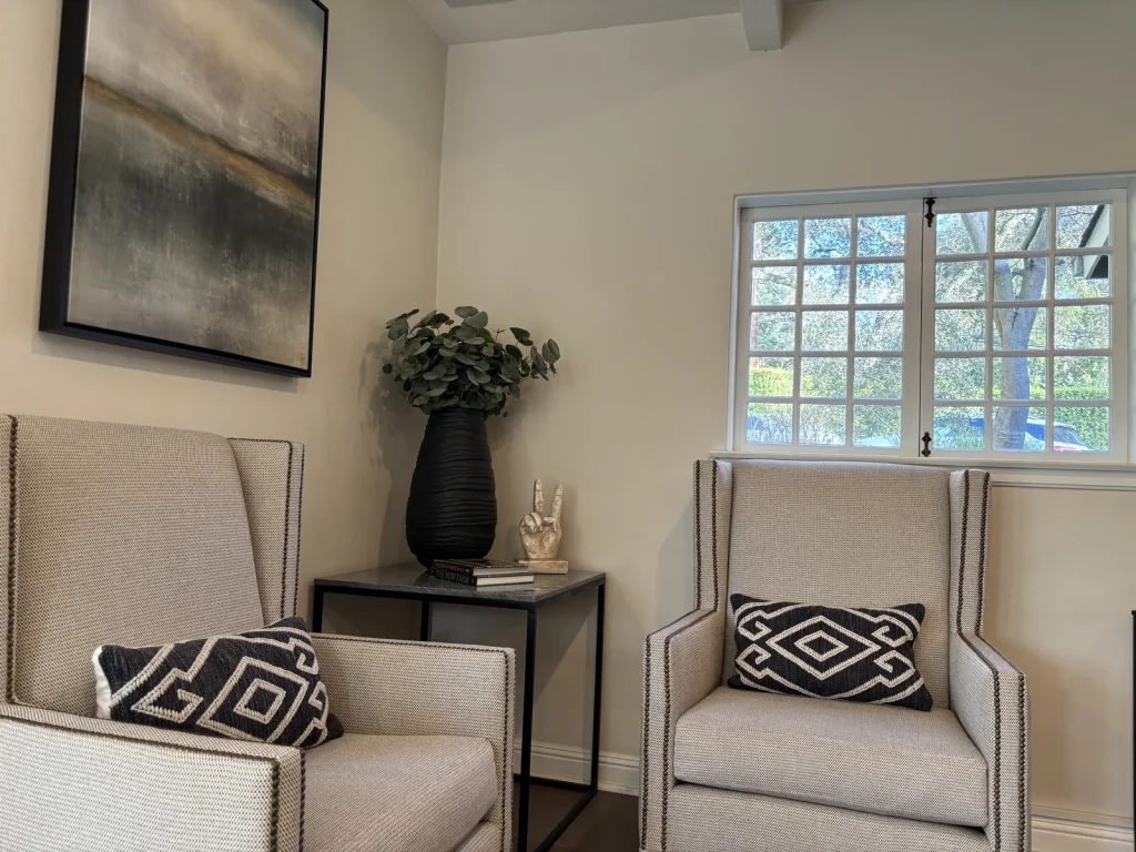 Designer-staged sitting area with two wingback armchairs, graphic block-print pillows, and abstract art in a Natomas home
