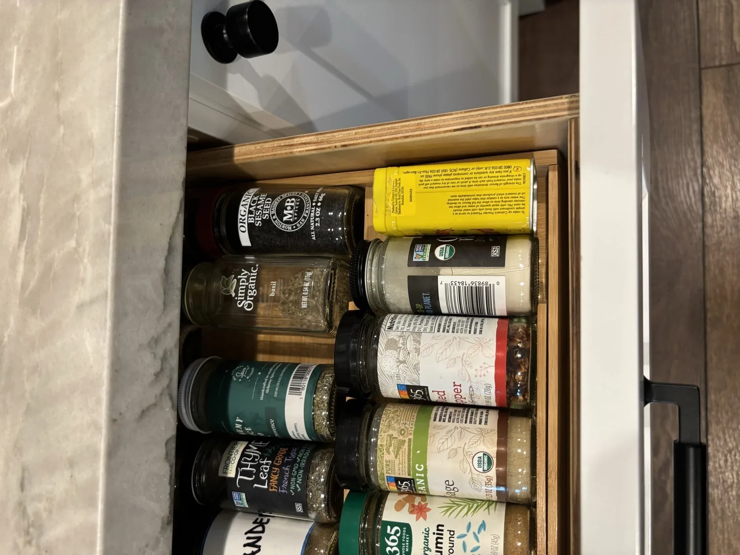 An open kitchen drawer organized with various spice jars and containers