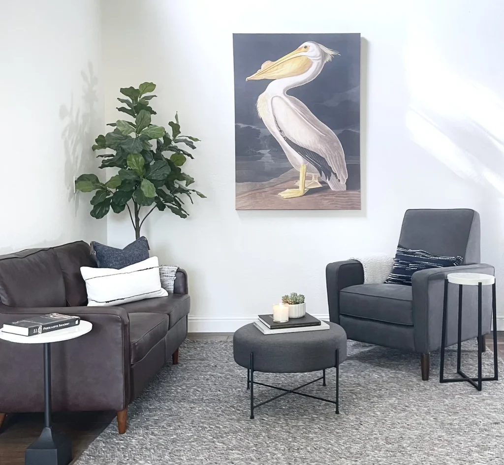 Staged living room with leather sofa, charcoal armchairs, and statement artwork, by Designed Curated, serving Penryn