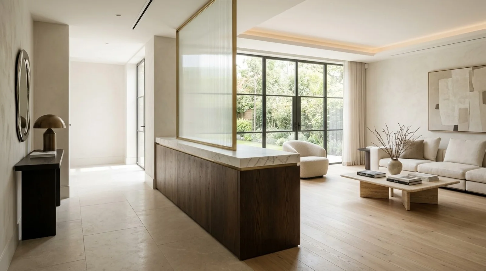 Walnut pony wall console with a marble cap topped by a brass-framed reeded glass screen, dividing an entry hall from a light-filled living room with steel-framed windows