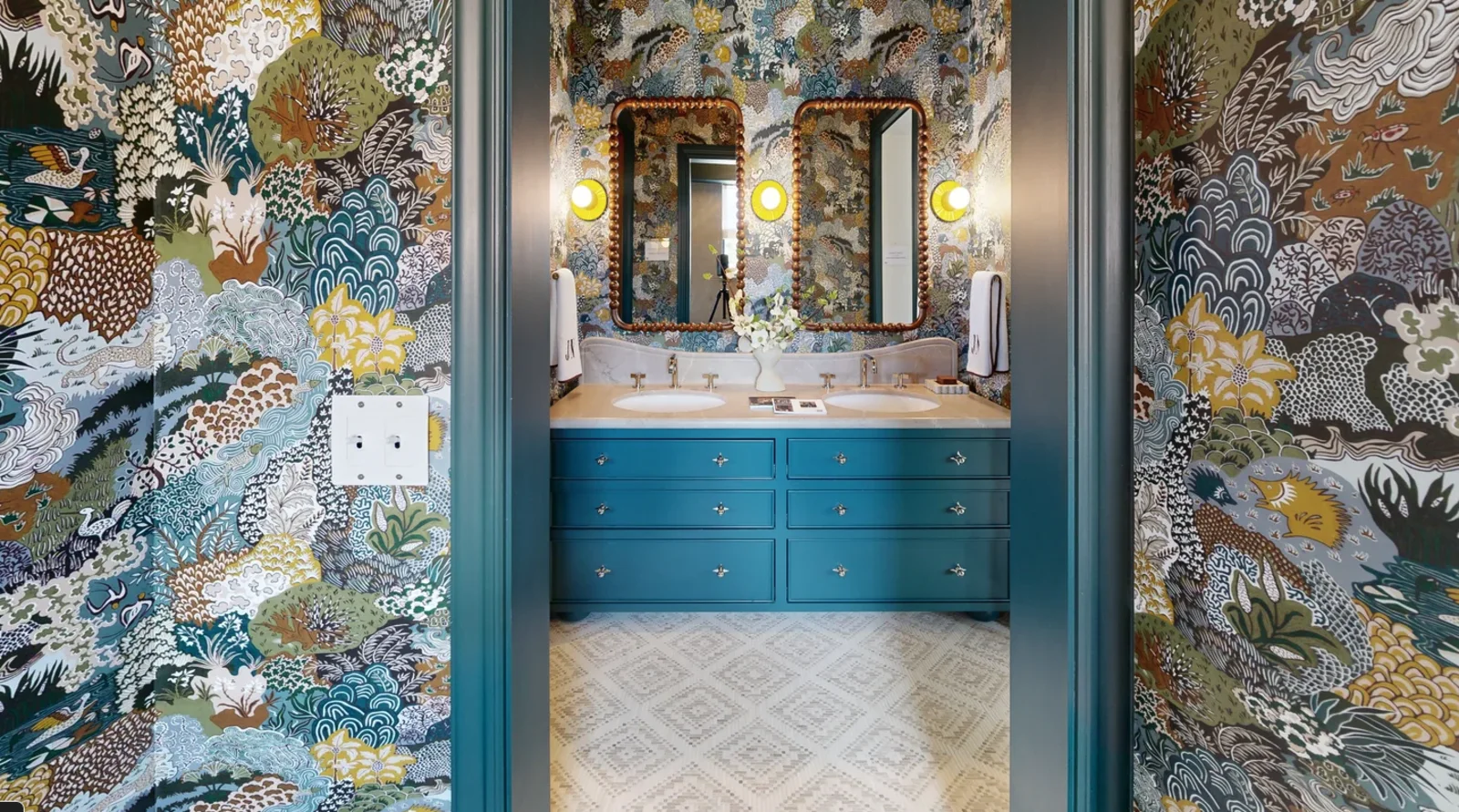 Bathroom with dense botanical wallpaper and teal painted double vanity at the 2315 Broadway showhouse