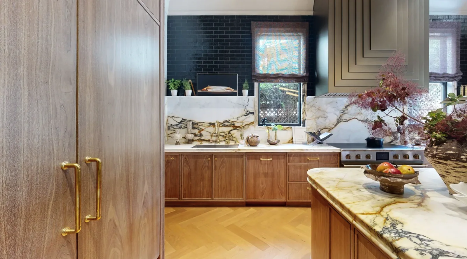 Walnut kitchen with full-height veined marble slab backsplash and brass hardware at the Pacific Heights showhouse