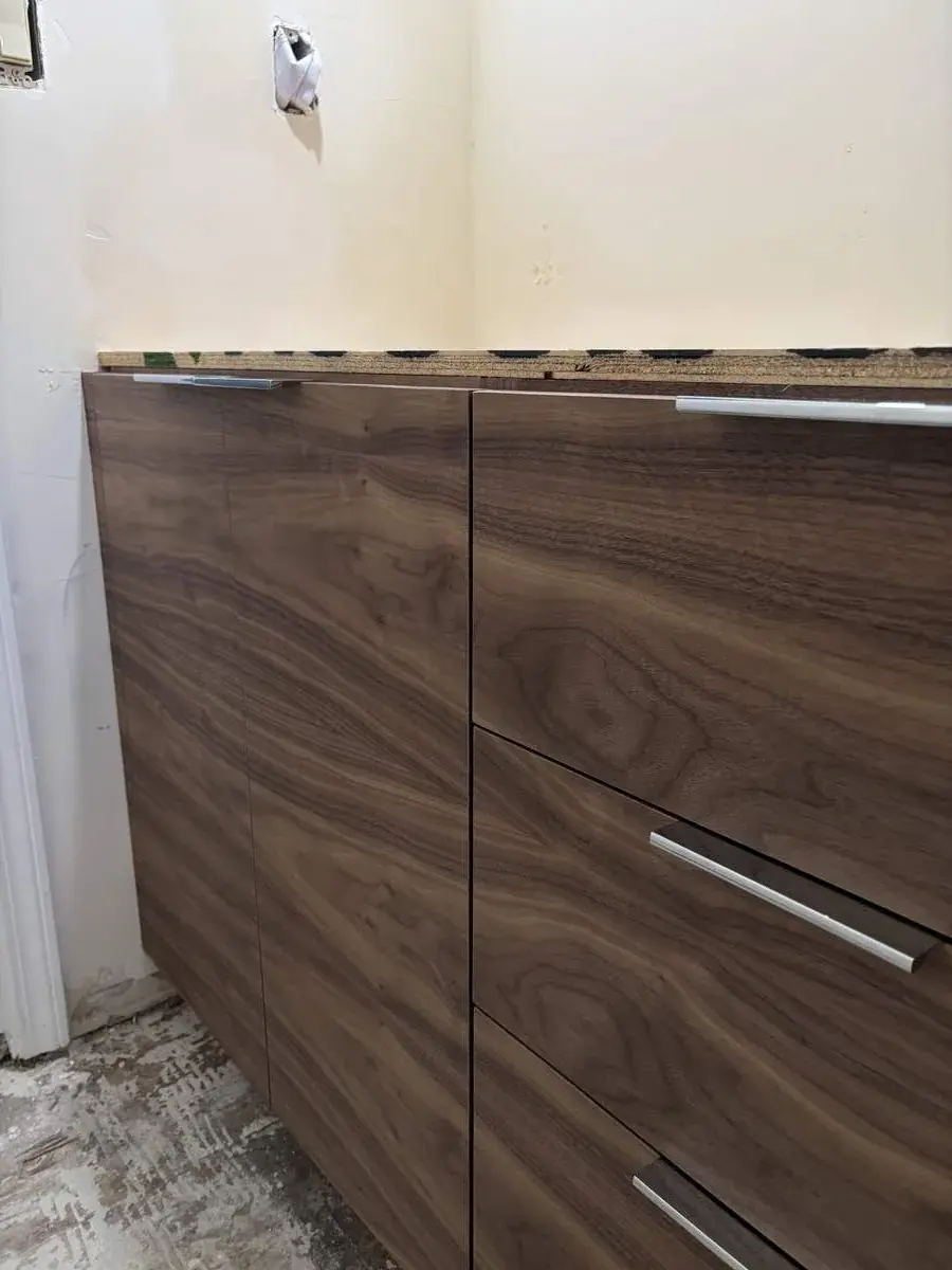 Close-up of unfinished wooden cabinets with metal handles in a room under renovation