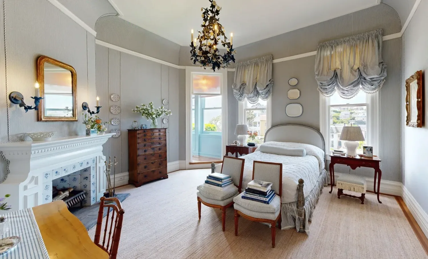 A traditionally styled bedroom with a fireplace, chandelier, and classic furniture
