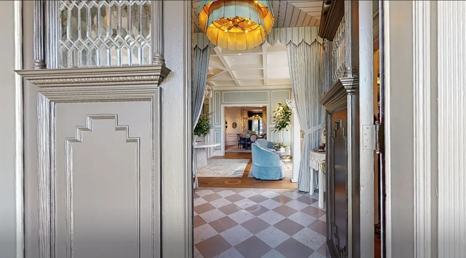View through an ornate doorway into a living and dining area with classic decor and pastel blue accents